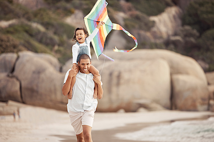 Family, kite flying and beach vacation with father and daughter walking while carrying on shoulders
